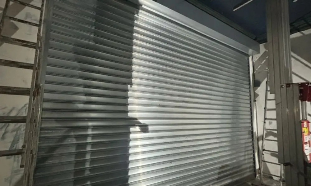 Rideau métallique industriel fermé sur façade d'entrepôt logistique en acier galvanisé